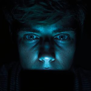 Digitalna zavisnost mladića sa licem obasjanim plavim ekranom.
